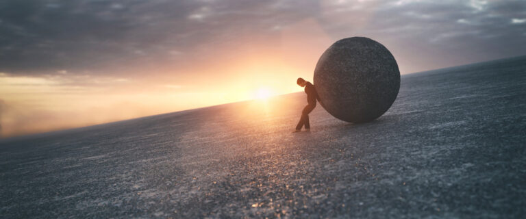 Man pushing boulder across desolate landscape.