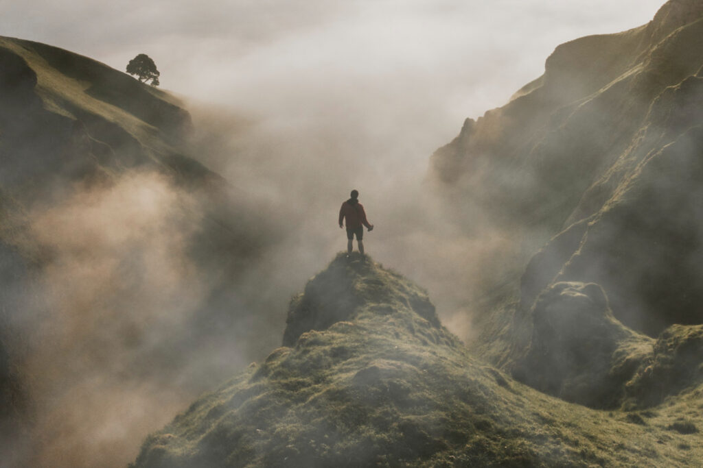 Man on cliff overlooking a valley symbolizing two paths in front of him