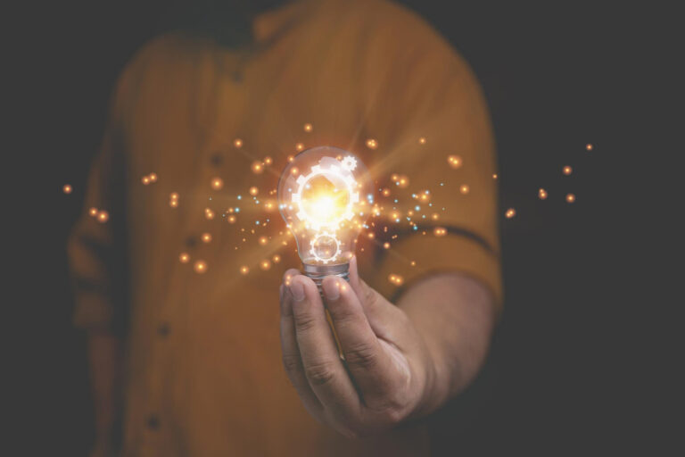 Illuminated light bulb being held by man in yellow shirt